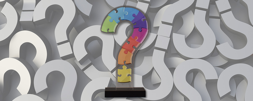 Question mark background with custom LaserCut™ Acrylic Award in the shape of a question mark in the foreground.